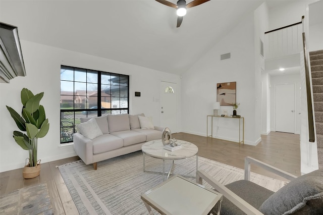 living area with visible vents, high vaulted ceiling, wood finished floors, stairway, and ceiling fan