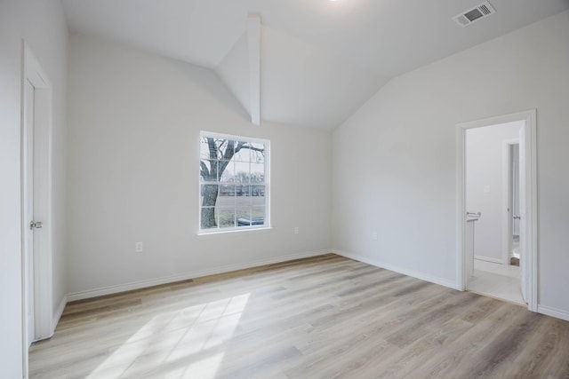 unfurnished bedroom featuring vaulted ceiling, connected bathroom, visible vents, and light wood-type flooring