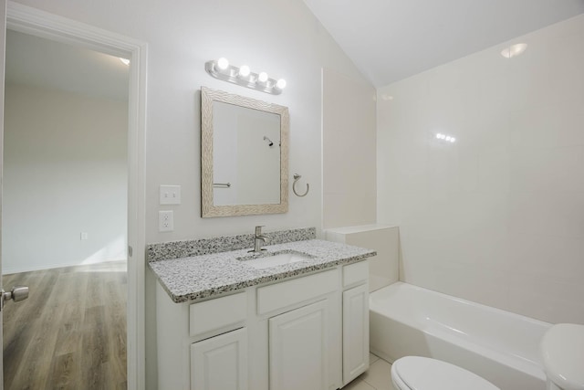 bathroom with vanity, wood finished floors, vaulted ceiling, bathing tub / shower combination, and toilet