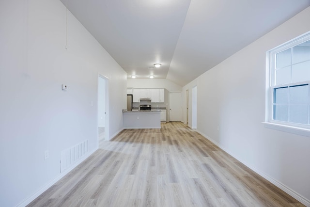 unfurnished living room with visible vents, baseboards, light wood-style floors, and vaulted ceiling