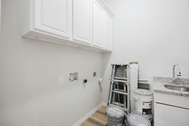 washroom with baseboards, cabinet space, electric dryer hookup, a sink, and light wood-style floors