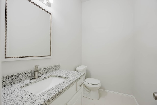 half bathroom with vanity, toilet, and baseboards