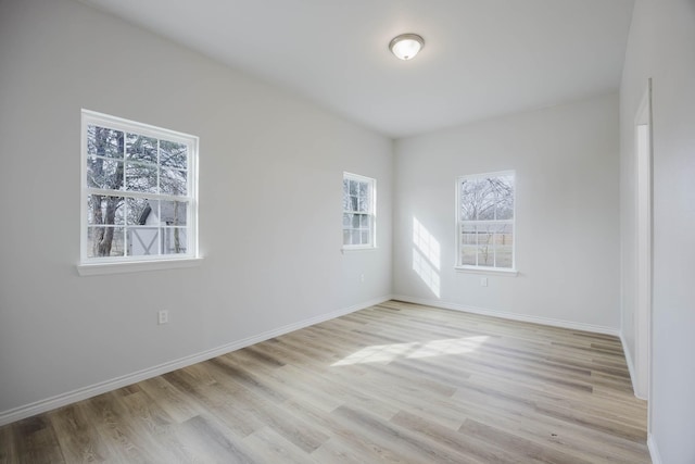 spare room with baseboards and light wood-style floors