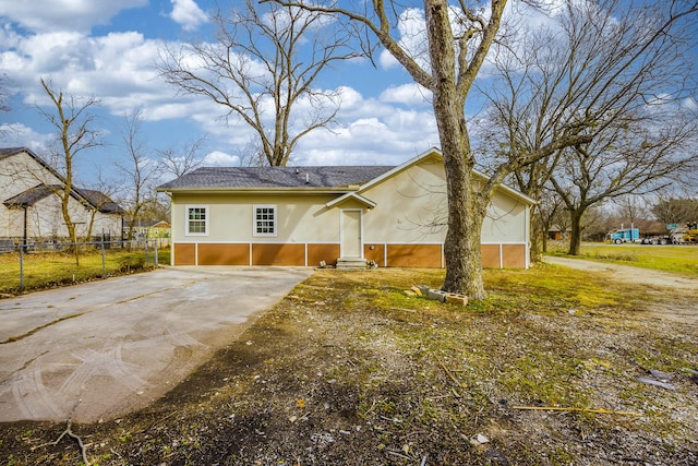 view of front of house featuring stucco siding, driveway, and fence