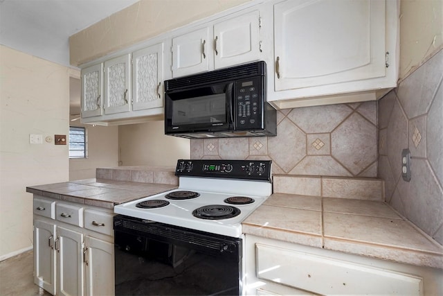 kitchen with tasteful backsplash, electric range oven, white cabinetry, black microwave, and tile counters