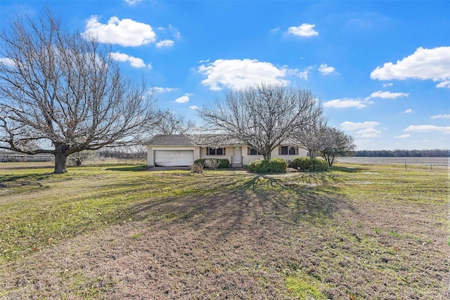 view of front of property featuring a front lawn, an attached garage, and a rural view