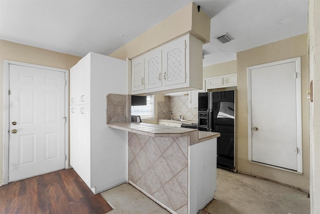 kitchen featuring visible vents, tile counters, a peninsula, black fridge with ice dispenser, and white cabinets