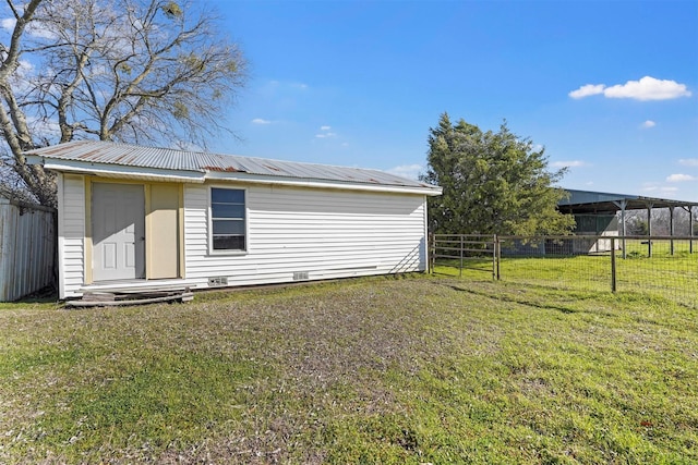 back of property with an outdoor structure, a lawn, fence, and metal roof