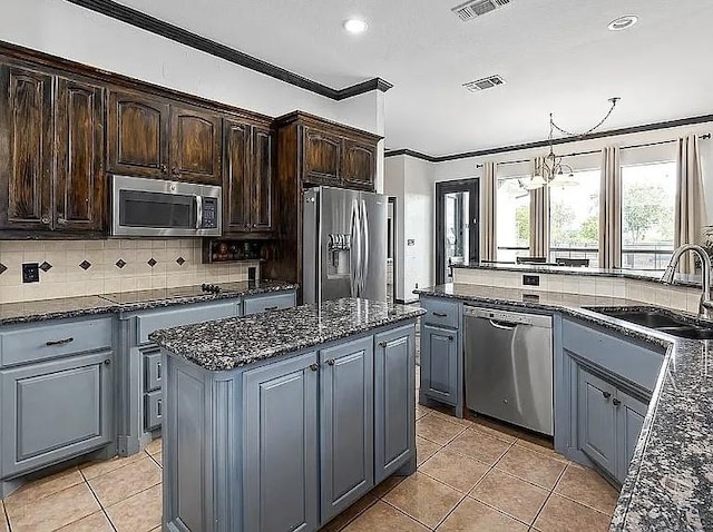 kitchen featuring ornamental molding, a sink, a kitchen island, appliances with stainless steel finishes, and decorative backsplash