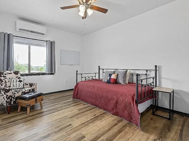 bedroom with an AC wall unit, wood finished floors, and a ceiling fan