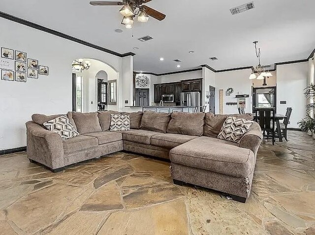 living room featuring ceiling fan with notable chandelier, crown molding, arched walkways, and visible vents