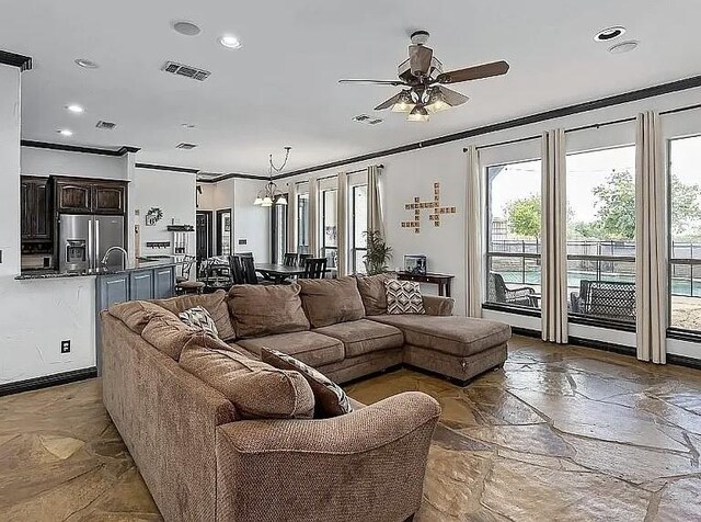 living area with visible vents, a ceiling fan, stone tile flooring, recessed lighting, and crown molding