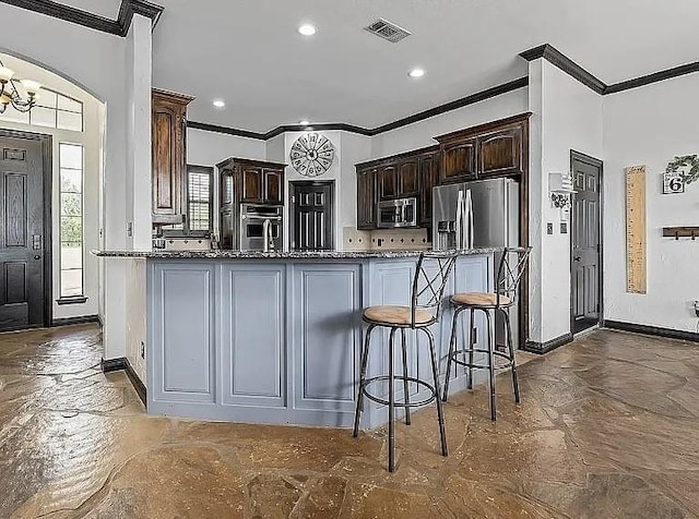 kitchen featuring visible vents, stainless steel appliances, dark brown cabinetry, crown molding, and a chandelier