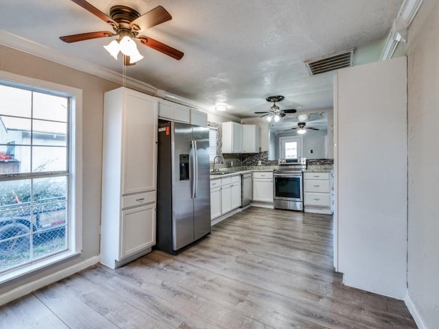 kitchen with a ceiling fan, visible vents, stainless steel appliances, light wood-style floors, and tasteful backsplash