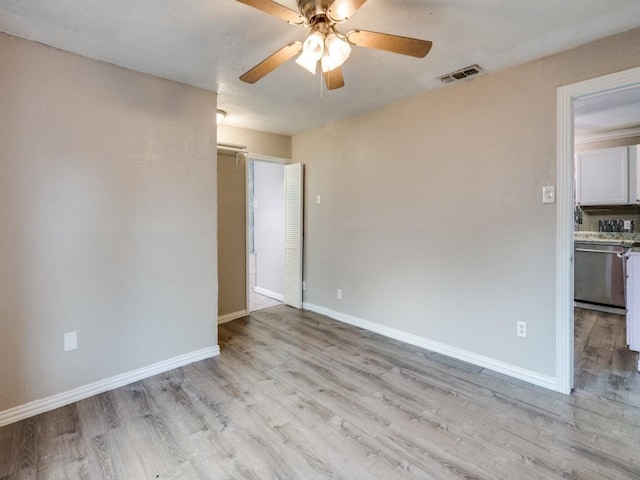 spare room with light wood finished floors, visible vents, baseboards, and ceiling fan