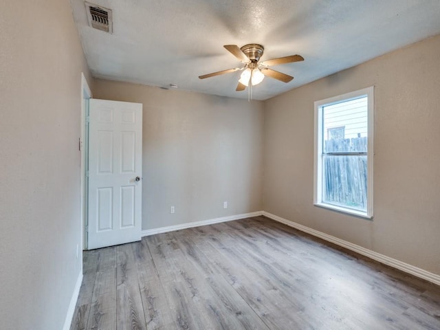 unfurnished room with wood finished floors, baseboards, visible vents, ceiling fan, and a textured ceiling