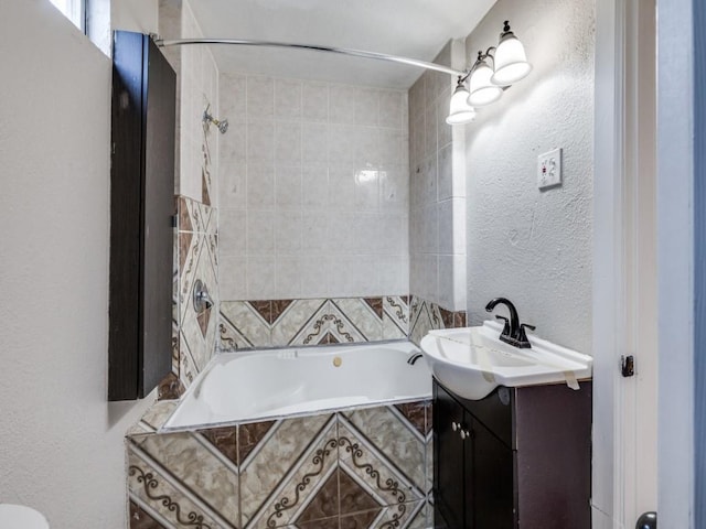 full bath featuring vanity, tiled shower / bath combo, and a textured wall