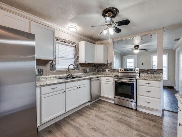 kitchen with backsplash, ceiling fan, ornamental molding, stainless steel appliances, and a sink