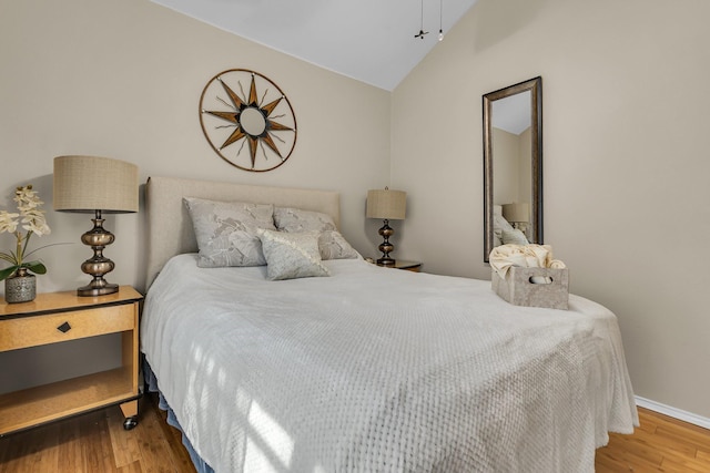 bedroom with baseboards, wood finished floors, and vaulted ceiling