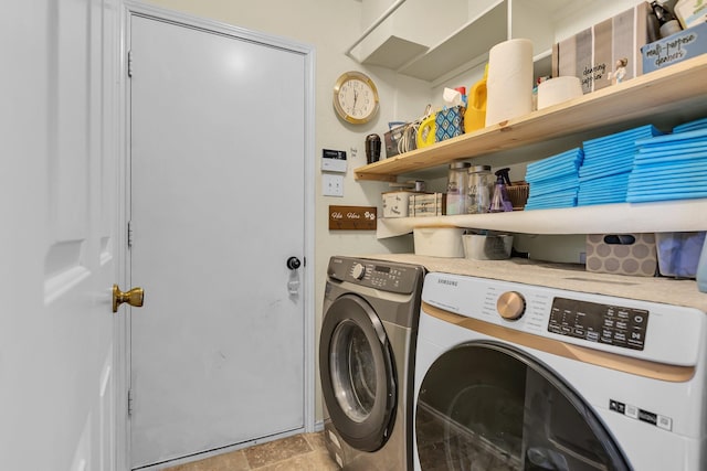 clothes washing area featuring washing machine and clothes dryer, laundry area, and stone finish floor