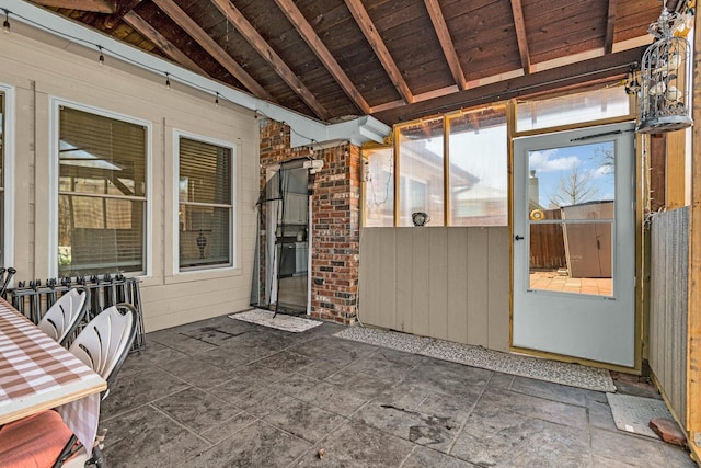 unfurnished sunroom featuring lofted ceiling with beams