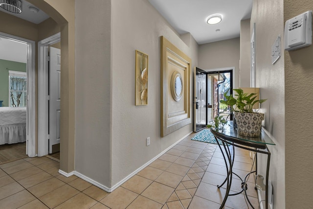 entryway featuring light tile patterned floors, baseboards, arched walkways, and a wealth of natural light