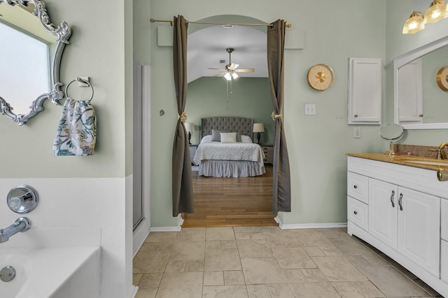 ensuite bathroom with vanity, a ceiling fan, baseboards, ensuite bath, and a bath