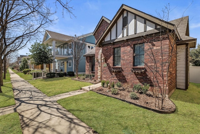 view of property exterior with brick siding, a yard, a balcony, and roof with shingles