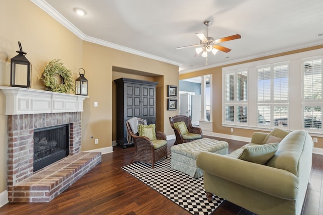 living area featuring a ceiling fan, baseboards, dark wood finished floors, a fireplace, and crown molding