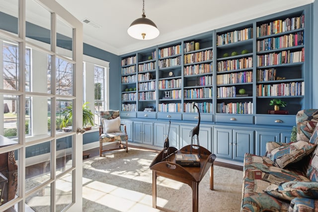 sitting room featuring bookshelves, visible vents, and ornamental molding