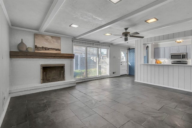 unfurnished living room featuring beamed ceiling, a brick fireplace, and ceiling fan