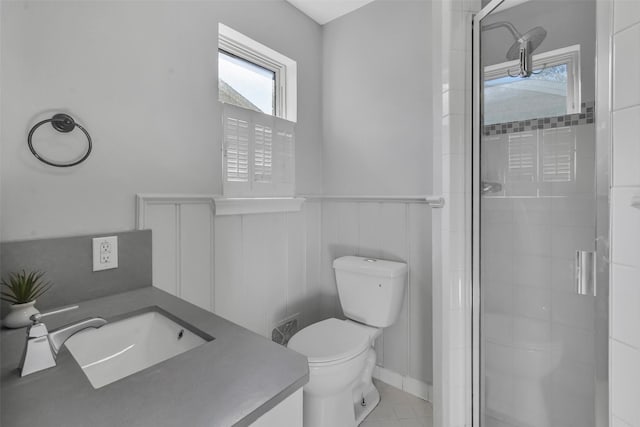 full bath featuring a wainscoted wall, toilet, a stall shower, and vanity