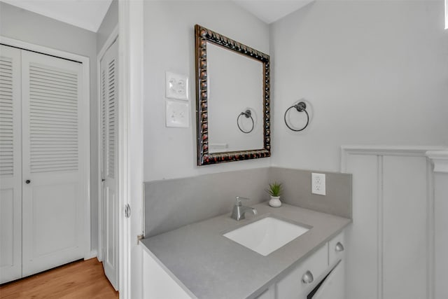 bathroom with a closet, wood finished floors, and vanity