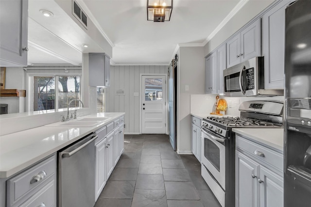 kitchen featuring visible vents, light countertops, ornamental molding, appliances with stainless steel finishes, and a sink