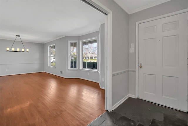 foyer entrance featuring dark wood-type flooring, a notable chandelier, crown molding, and baseboards