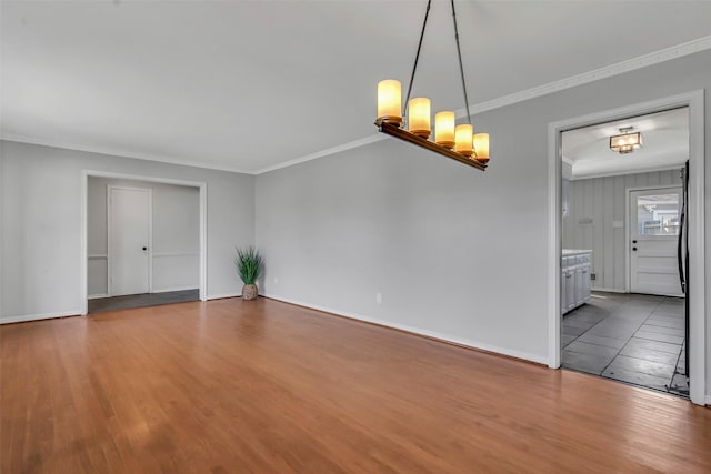 unfurnished room with baseboards, a notable chandelier, wood finished floors, and ornamental molding