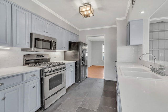 kitchen featuring a sink, backsplash, stainless steel appliances, crown molding, and light countertops