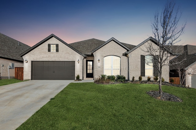 french country home with brick siding, a front lawn, fence, a garage, and driveway