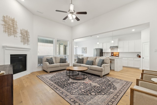 living area featuring a ceiling fan, visible vents, recessed lighting, light wood-style floors, and a glass covered fireplace