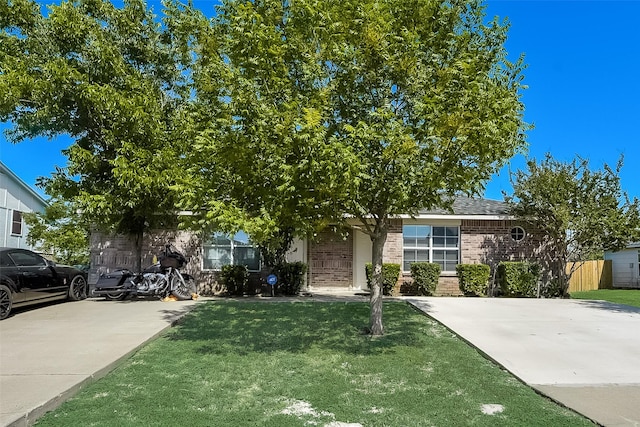 view of property hidden behind natural elements featuring a front yard and brick siding