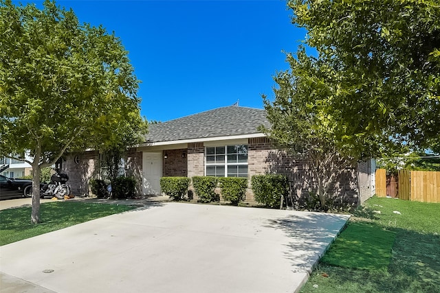 view of front of home featuring a front lawn, fence, brick siding, and a shingled roof