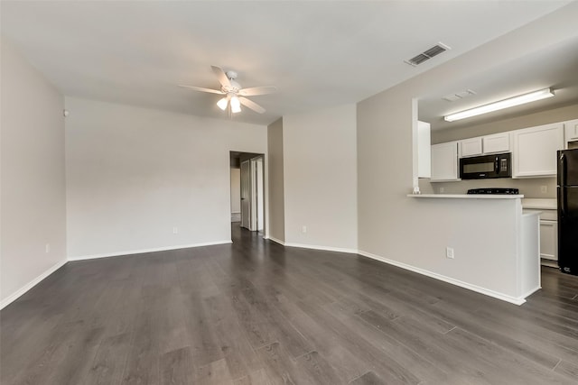 unfurnished living room featuring dark wood-type flooring, a ceiling fan, visible vents, and baseboards