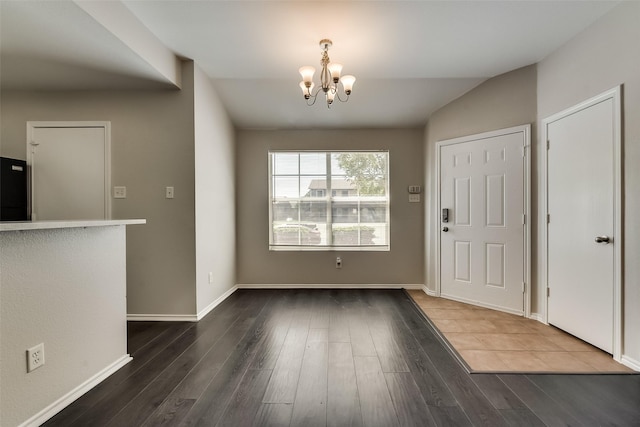 foyer featuring baseboards, a chandelier, dark wood-style flooring, and vaulted ceiling