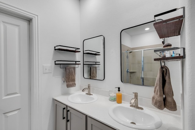 bathroom with double vanity, a stall shower, and a sink