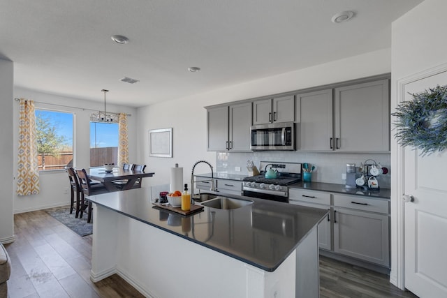 kitchen featuring gray cabinets, a sink, dark countertops, backsplash, and stainless steel appliances