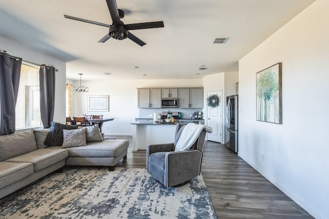 living room with baseboards, visible vents, dark wood-style flooring, and ceiling fan