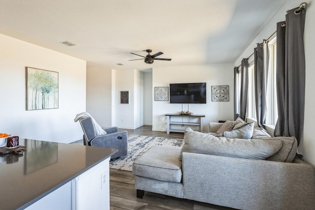 living area featuring a ceiling fan, dark wood-style floors, and visible vents