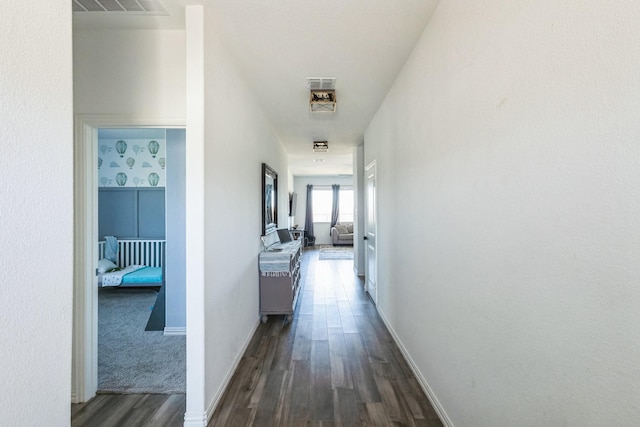 hall featuring visible vents, baseboards, and dark wood-type flooring