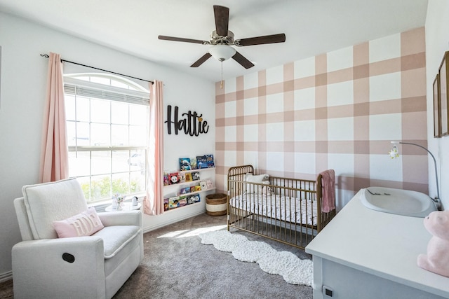 carpeted bedroom featuring a sink, a nursery area, and ceiling fan