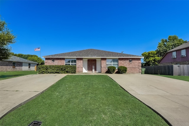 view of front of property featuring a front yard, fence, brick siding, and roof with shingles